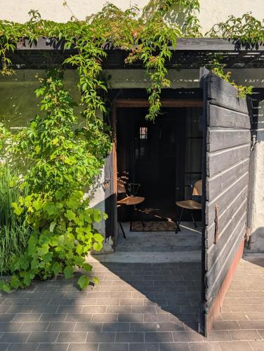 an open door to a patio with tables and plants at Noliktava No 5 in Kuldīga