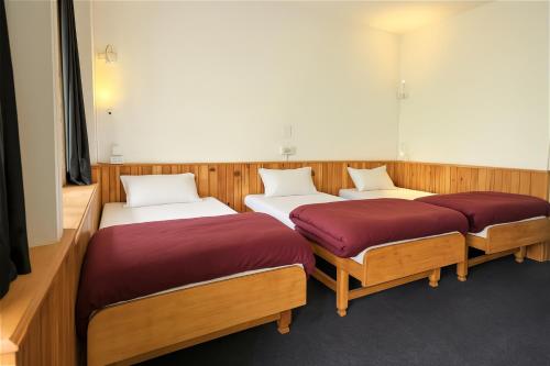 three beds in a room with wood paneling at Beholden Stay and Cafe - A Luxury Boutique Hotel in Manali in Manāli