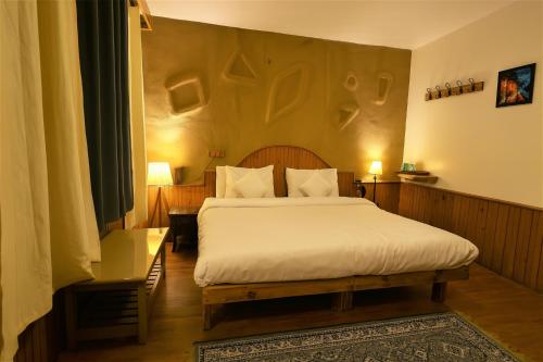a bedroom with a large bed with white sheets at Beholden Stay and Cafe - A Luxury Boutique Hotel in Manali in Manāli