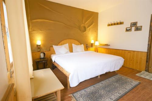 a bedroom with a large white bed in a room at Beholden Stay and Cafe - A Luxury Boutique Hotel in Manali in Manāli