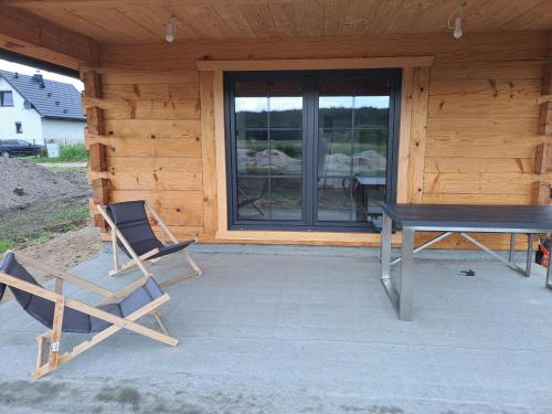 ein Tisch und Stühle auf einer Terrasse vor einer Hütte in der Unterkunft Drewno i Len in Debina