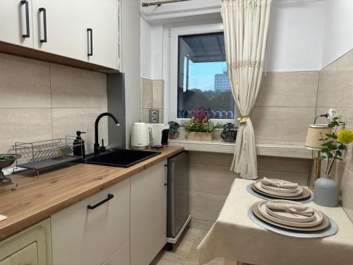 a kitchen with white cabinets and a sink and a window at Studio PANORAMIC with Balcony and Parcul Unirii view in Alba Iulia