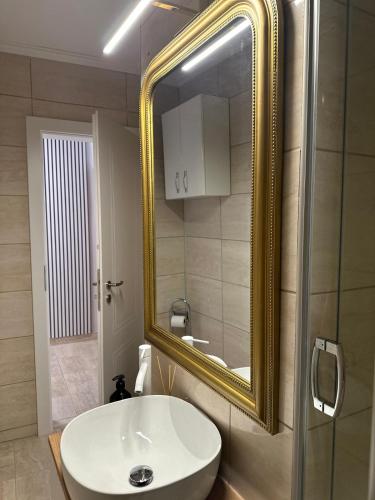 a bathroom with a white sink and a gold mirror at Studio PANORAMIC with Balcony and Parcul Unirii view in Alba Iulia