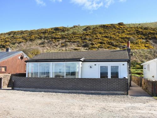 a house on the beach with a hill in the background at Ludlow Bank in Caulderton
