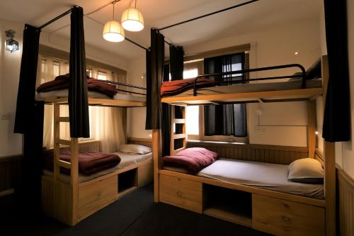 a room with three bunk beds in a hostel at Beholden Stay and Cafe - A Luxury Boutique Hotel in Manali in Manāli
