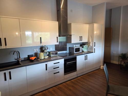 a kitchen with white cabinets and a microwave at Luxury City Center Apartment in Liverpool