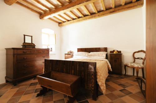 a bedroom with a bed with a dresser and a chair at Corte del Catria in Chiaserna