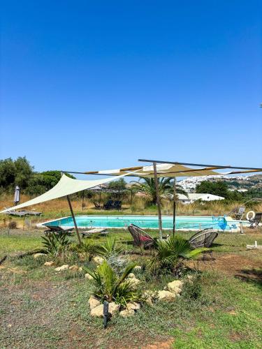 a pool with a tan umbrella and some chairs at casa entre mer et montagne in Arcos de la Frontera
