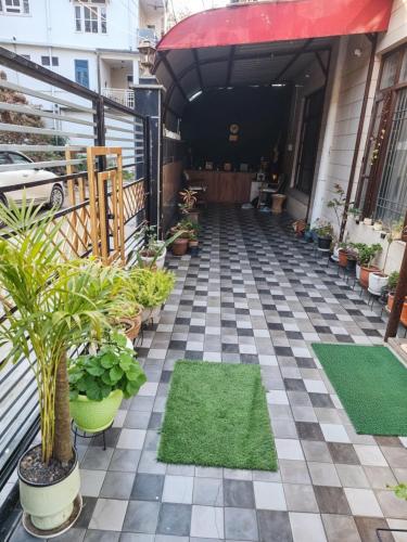 a patio with plants and grass on a checkered floor at Waterfront Homestay 2BHK Free Bonfire By Homeyhuts in Mandi