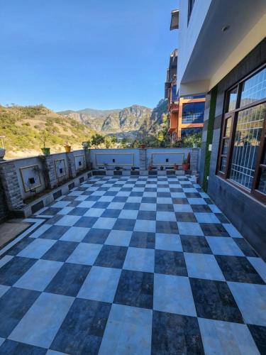 a checkered floor in a building with mountains in the background at Waterfront Homestay 2BHK Free Bonfire By Homeyhuts in Mandi