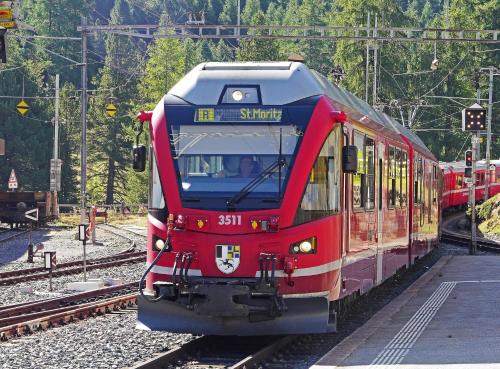 a red train is traveling down the tracks at Zentral Altstadt Chur - Bahnhofsnah - Ferienwohnung - Bernina Express - Solution-Grischun in Chur