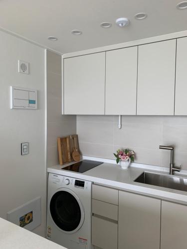 a white kitchen with a washing machine and a sink at Yanggaeng Casa in Busan