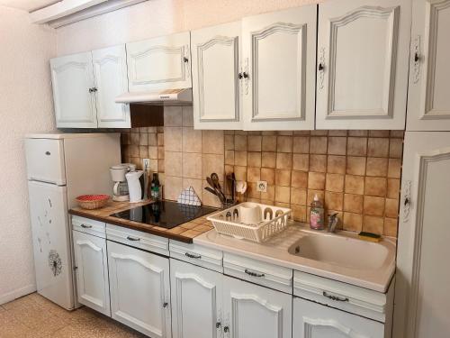 une cuisine avec des armoires blanches et un évier dans l'établissement Studio Méditerranée au pied des Arènes, à Arles