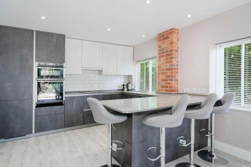 a kitchen with white cabinets and a table and stools at Chalet Gerrards Cross in Gerrards Cross