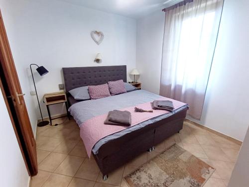 a bedroom with a large bed with pink pillows at Levendula Apartman Zalakaros in Zalakaros