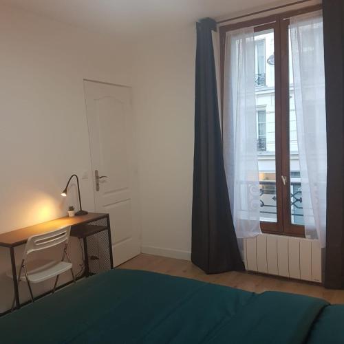 une chambre avec un lit, un bureau et une fenêtre dans l'établissement Studio cosy, quartier canal Saint-Martin, à Paris
