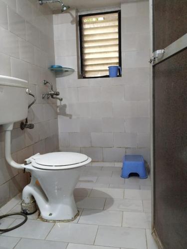 a bathroom with a toilet and a window at Savali Cottage in Nagaon