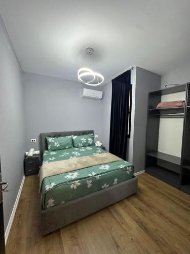 a bedroom with a bed with a green comforter at Holiday Apartments in Tirana