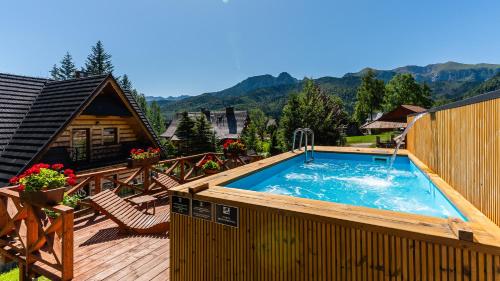 a large swimming pool on a deck with a house at Aparthotel Delta Royal in Kościelisko
