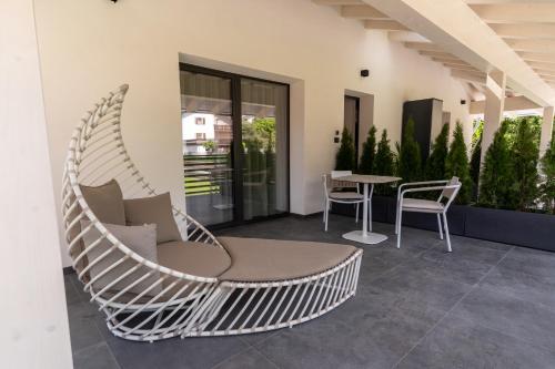 a white rattan chair and table on a patio at Fai le Coccole in Fai della Paganella