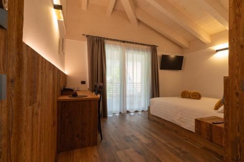 a bedroom with a bed and a large window at Fai le Coccole in Fai della Paganella