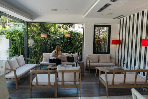 a woman sitting on a couch in a living room at Hotel Sitges in Sitges