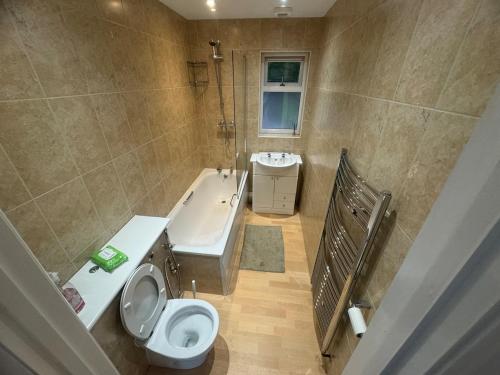 a bathroom with a toilet and a tub and a sink at 2 Bedroom-House-Sleeps 5 In Front Horley Station -Near Gatwick Airport in Horley