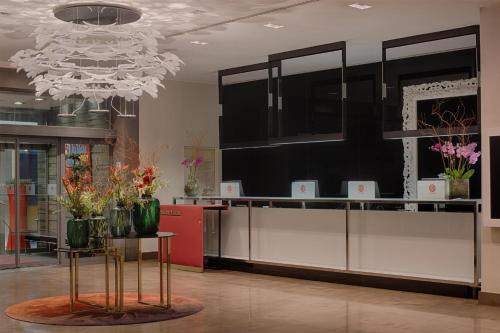 a lobby with a reception desk with flowers on it at NH Collection Milano President in Milan