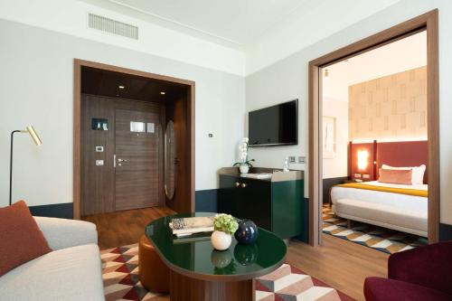 a hotel room with a bed and a living room at NH Collection Milano President in Milan