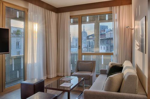 a living room with a couch and a large window at NH Collection Milano President in Milan