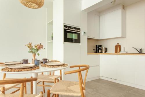 a white kitchen with a table and chairs at Bright and Cozy Apartment in Oostende in Ostend