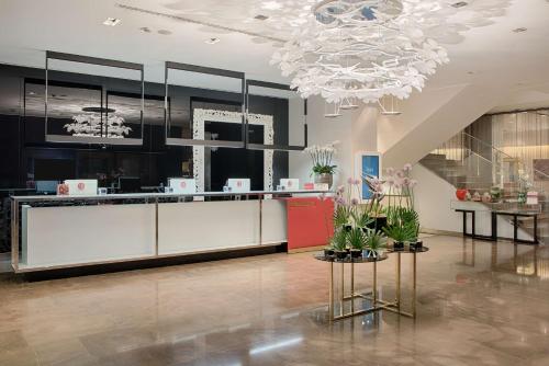 a lobby with a reception desk and a chandelier at NH Collection Milano President in Milan