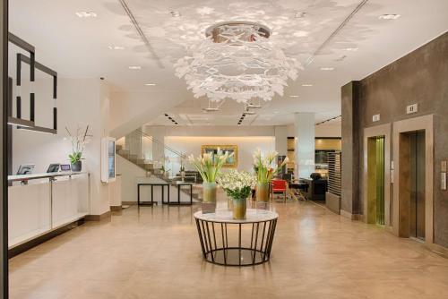 a lobby with a chandelier and a table with flowers on it at NH Collection Milano President in Milan