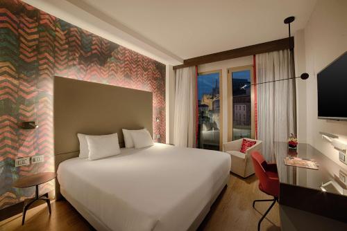 a bedroom with a large white bed and a window at NH Collection Milano President in Milan