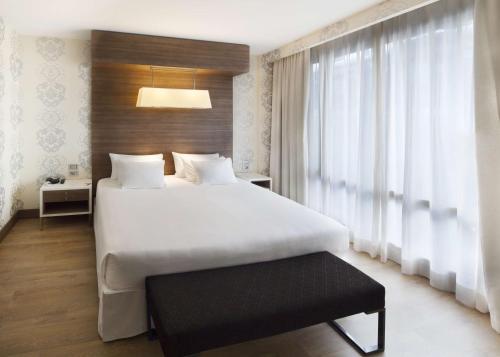 a bedroom with a large white bed and a window at NH Collection Milano President in Milan