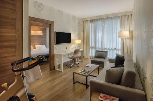 a living room with a couch and a bed at NH Collection Milano President in Milan
