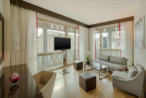 a living room with a couch and a tv at NH Collection Milano President in Milan