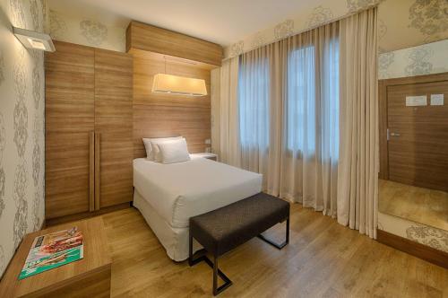a bedroom with a bed and a table and a window at NH Collection Milano President in Milan