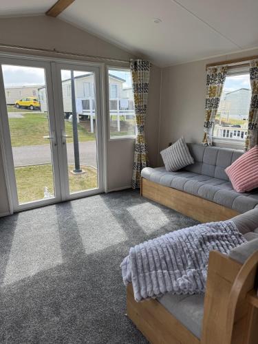 a living room with a couch and sliding glass doors at Well equipped beach caravan in Leysdown-on-Sea
