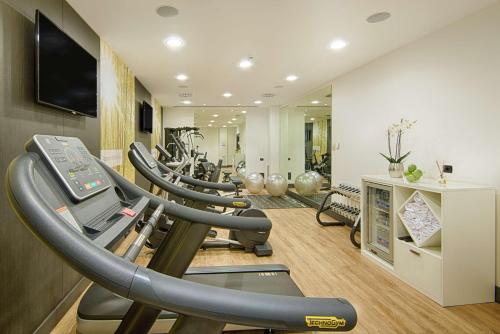 a gym with several treadmills and a row of exercise bikes at NH Collection Milano President in Milan