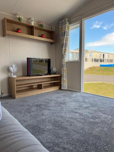a living room with a tv and a large window at Well equipped beach caravan in Leysdown-on-Sea