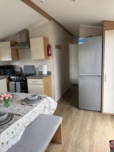a small kitchen with a refrigerator and a table at Well equipped beach caravan in Leysdown-on-Sea