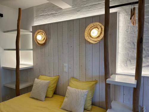a bedroom with a bed with yellow pillows and two lights at Z' Evita in Nieuwpoort