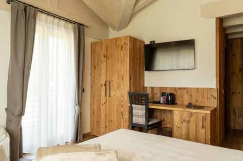a bedroom with a bed and a desk and a window at Fai le Coccole in Fai della Paganella