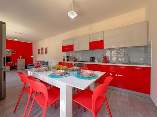 a kitchen with red cabinets and a white table with red chairs at Relax & Views in Le Marche by Host Hero in Morrovalle