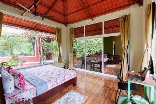 a bedroom with a bed and a large window at Leafyden Forest Cottages in Talekhār