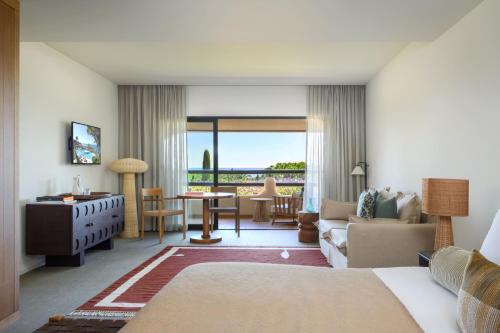 a living room with a couch and a dining room at Vilalara Grand Hotel Algarve in Armação de Pêra