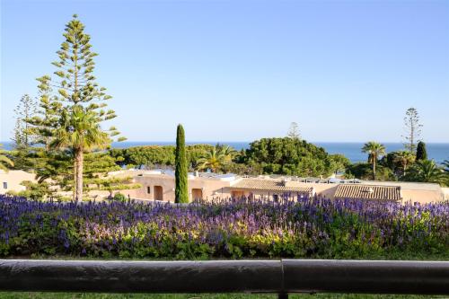 a garden with purple flowers and palm trees at Vilalara Grand Hotel Algarve in Armação de Pêra