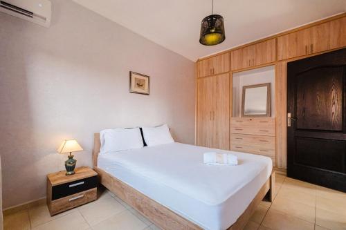 a bedroom with a white bed with a night stand and a lamp at Cosy 2BR Apartment in marrakech in Marrakech