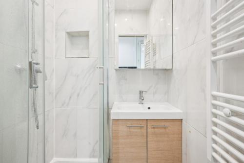 een witte badkamer met een wastafel en een douche bij Beautiful renovated studio metro in Levallois-Perret